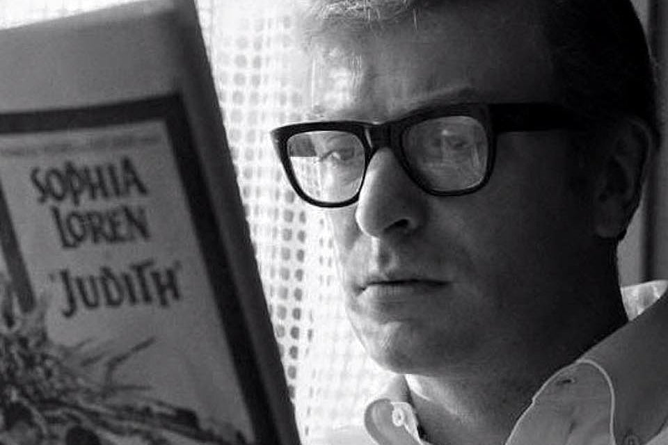 Michael Caine wearing glasses reading newspaper