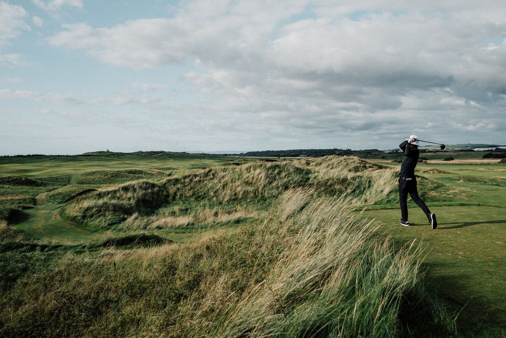 Erik Anders Lang swinging golf club on grassy hillside